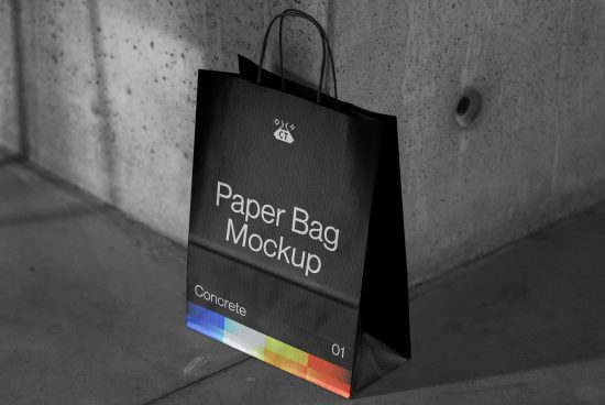 Stylish paper shopping bag mockup with colorful branding, resting against a concrete wall, suitable for graphic designers.
